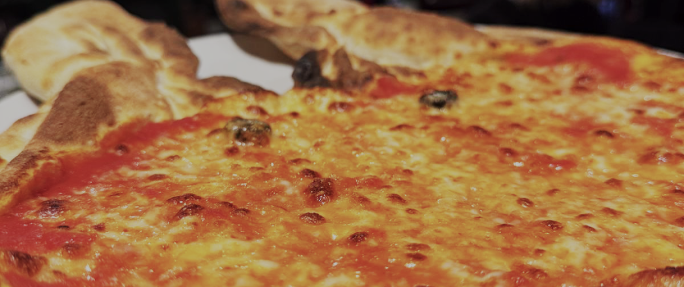 pizza margherita con la sua forma classica con aggiunta di crosta che fa pensare sia la pala da pizzaiolo